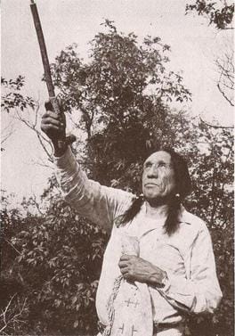 An image of Lakota Leader John Fire Lame Deer holding a sacred ceremonial pipe, in a black and white image