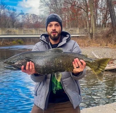 man holding a salmon caught fishing onhe rocky river
