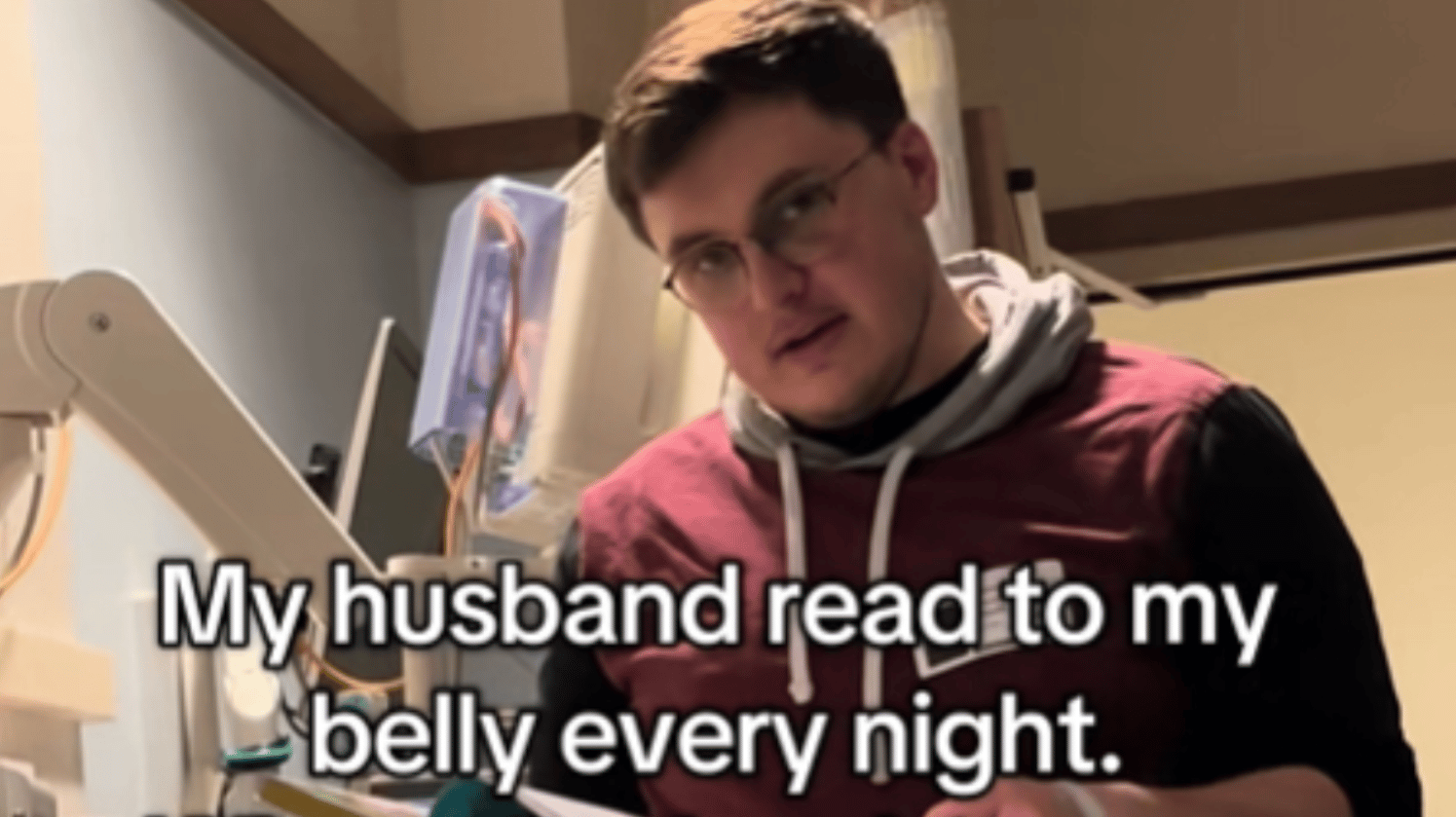 Close up of a man as he stands over his baby in the NICU. He holds a book in his hand, reading. He's looking up at the camera. Text on the image reads: My husband read to my belly every night