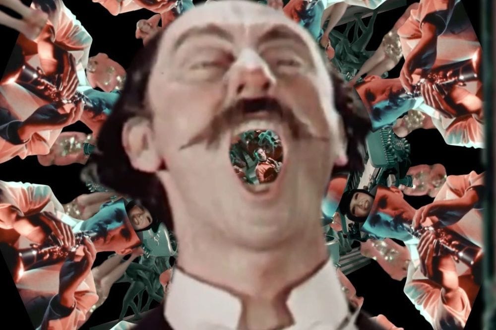 Frame from Andrea Hale's 1st place film, "Rhapsody, Reimagined," featuring a man with a handlebar mustache. Behind him, and visible through his open mouth, are kaleidoscopic, repeated images from the 1930 film King of Jazz.