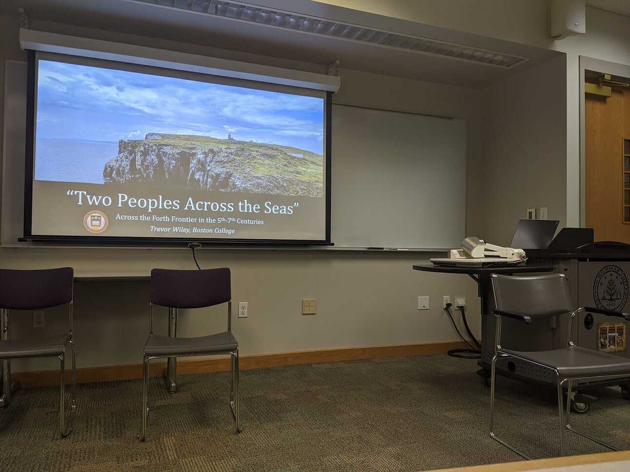 The front of a classroom, with a powerpoint on the screen