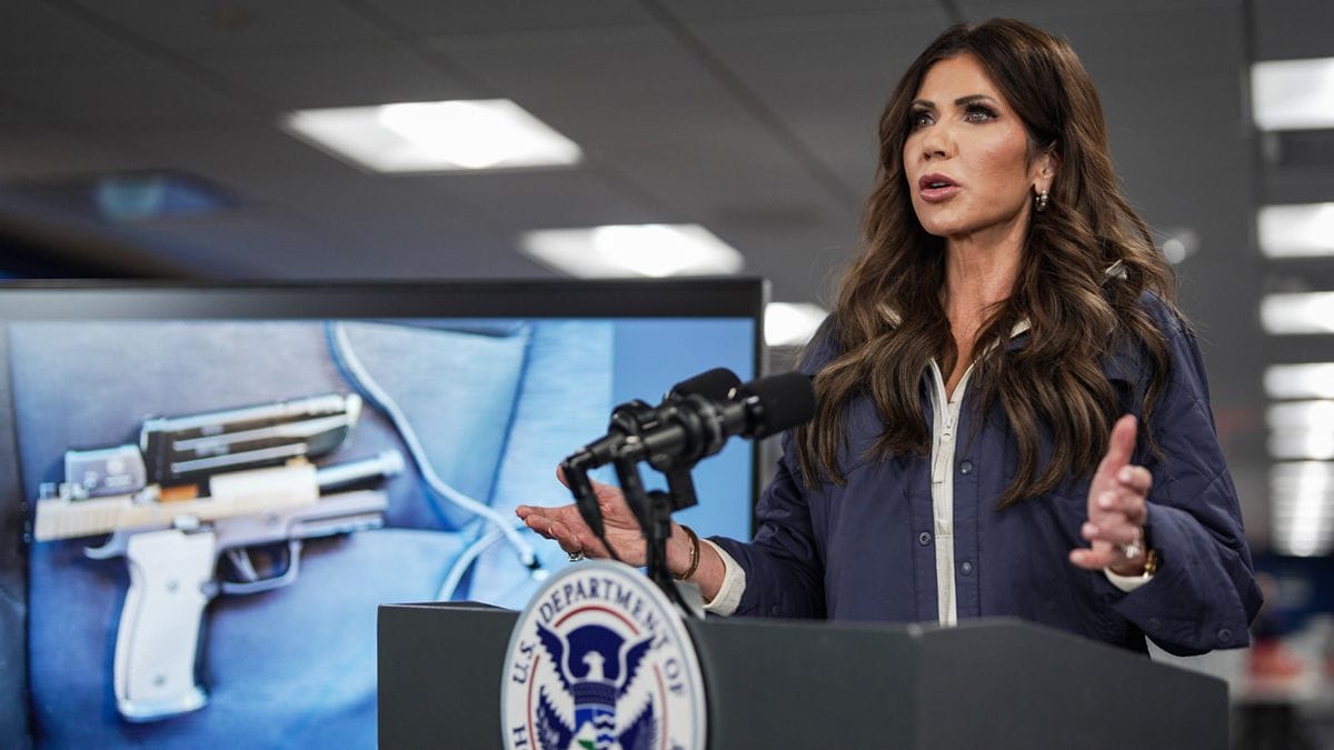 A white woman stands behind a podium. To her left, a gun is pictured.