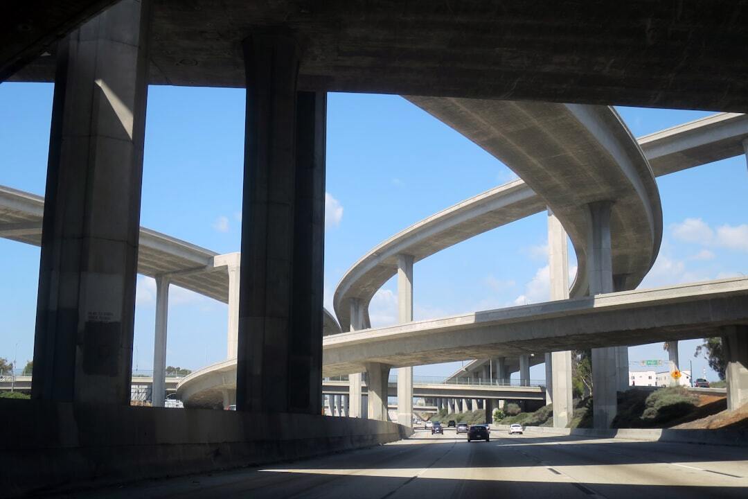 A driver's-eye view of cars driving along the 110 Freeway in Los Angeles as they pass under the soaring interchange with the 105 Freeway. This is quintessential L.A. architecture and engineering, and a typical view for thousands of people every commute. Another sunny day in paradise.