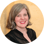 An image of Kay Coughlin, a white woman with gray hair, smiling, wearing a dark-colored professional blouse