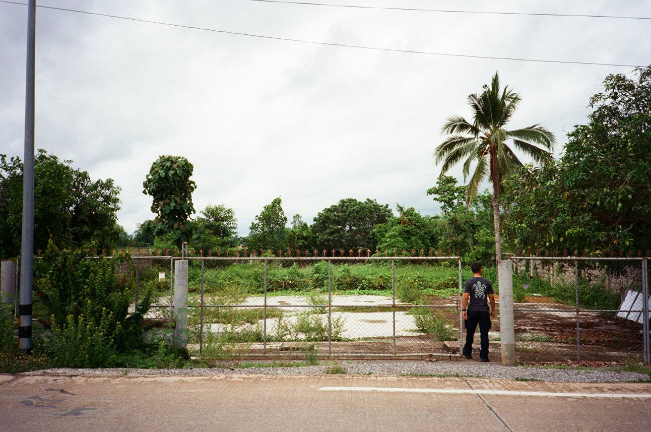 The empty lot where our house used to be. My brother looks in through the gate.