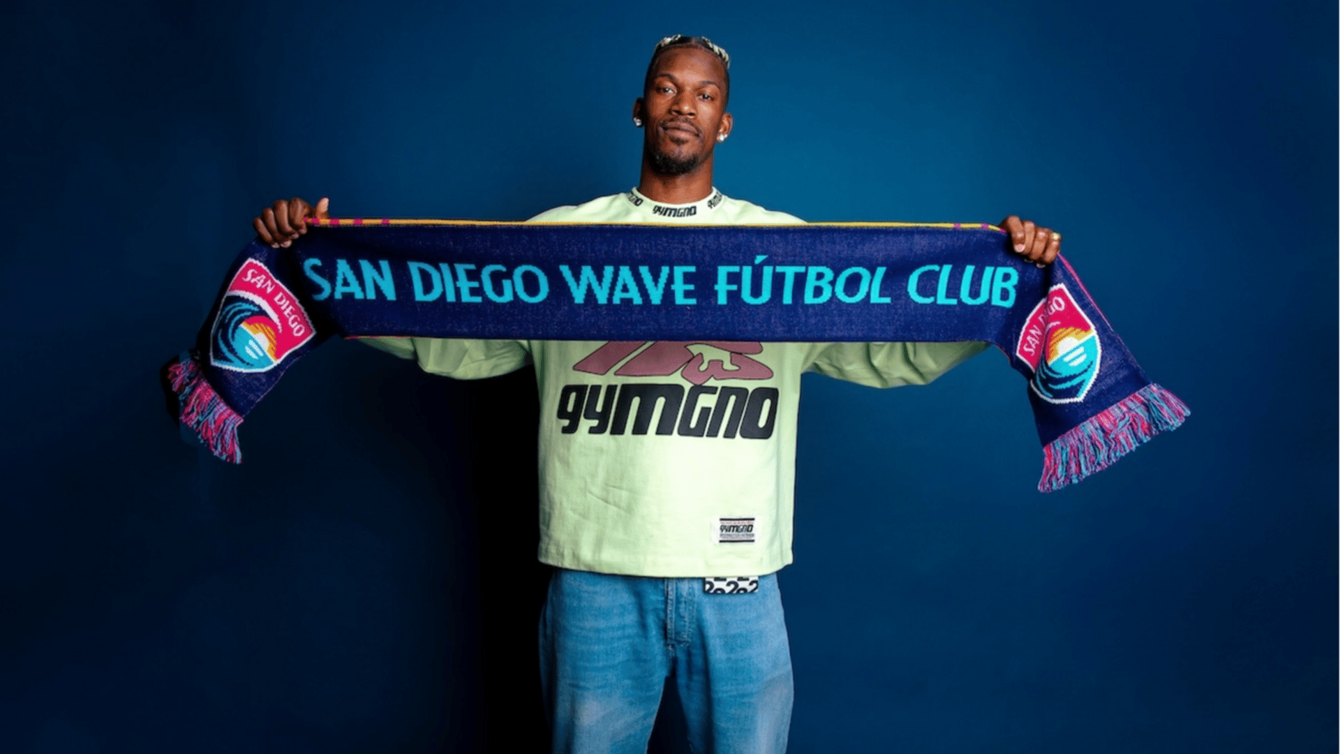 Jimmy Butler holds up a San Diego Wave scarf in a posed photograph