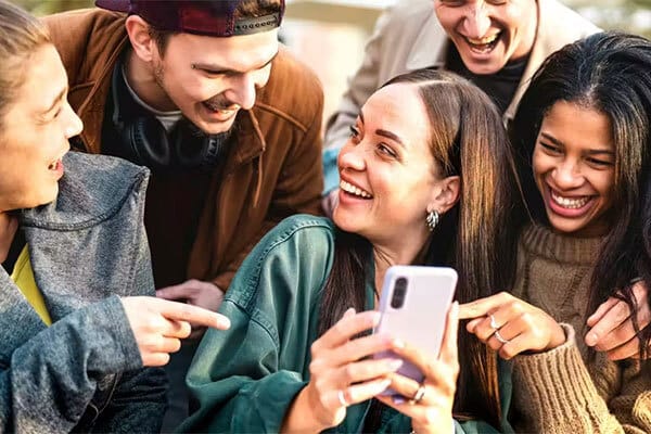 Teens laugh at a phone together.
