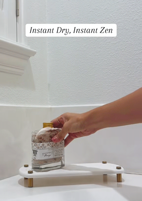 A calming scene unfolds as bath salt is gently poured into a tub, followed by a few drops of bath oil. A candle is placed beside the tub, then lit, creating a warm, soothing glow. The scene transitions to showcase the Twinkle Moment Instant Dry Sink Caddy in action, with water quickly evaporating to highlight its fast-drying performance, perfectly complementing the serene, self-care atmosphere.