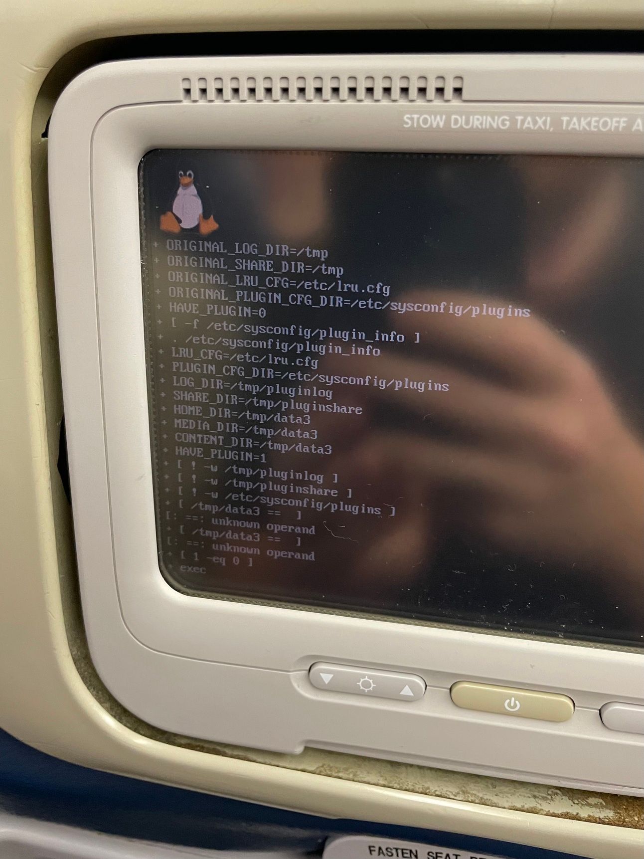 An inflight entertainment screen displays a Linux startup screen.