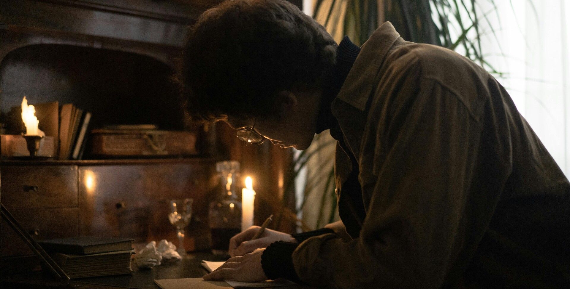 Man writing reflections in a notebook by candlelight, planning solutions to life’s challenges.