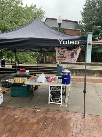 It is raining and a canopy is set up over the serving table