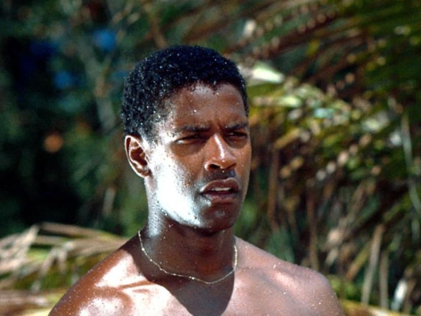  Screenshot of Denzel Washington in The Mighty Quinn, dressed in island attire with a badge, set against a tropical backdrop.