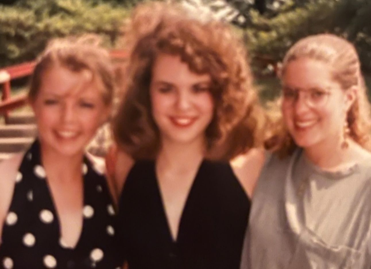 Three white women in their early 20s, smiling with their arms around each other. The image is a slightly fuzzy snapshot from about 1994.