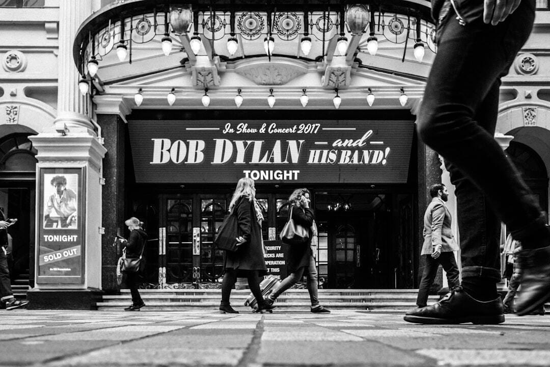 People walk past the London Palladium advertising a Bob Dylan show.
