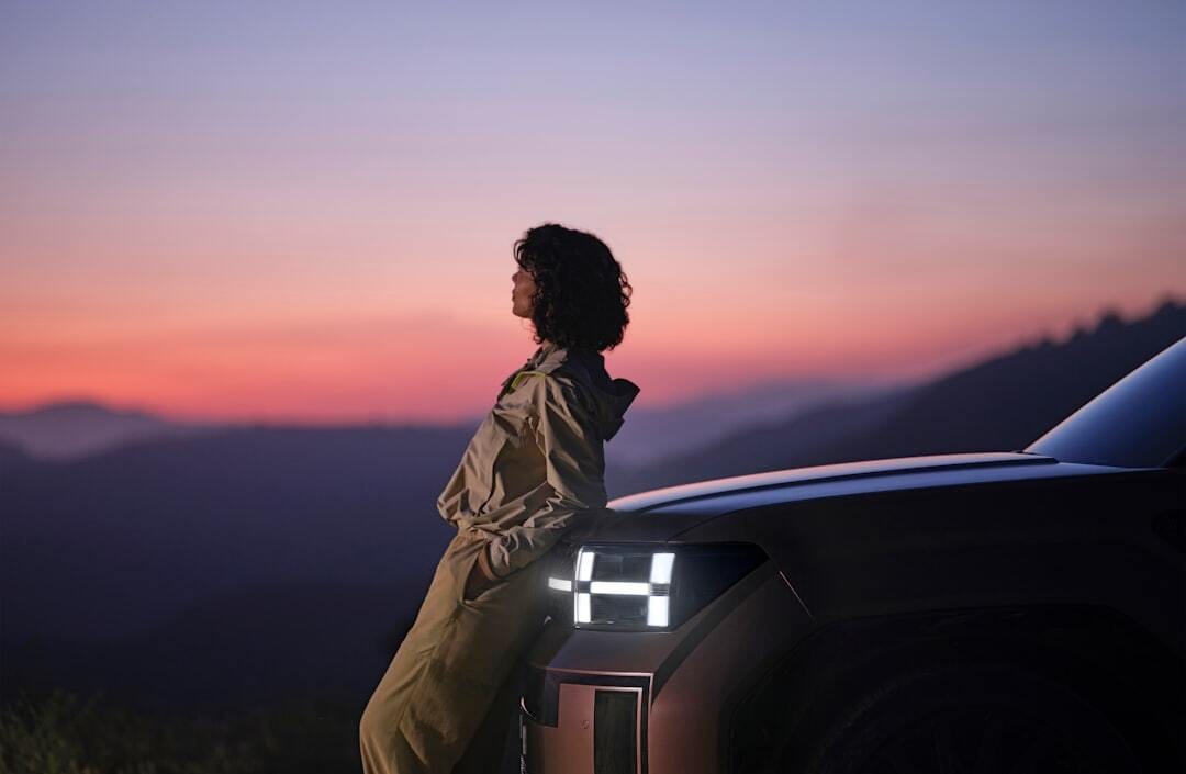 A person watching the sunset while leaning on the Hyundai SANTA FE.
