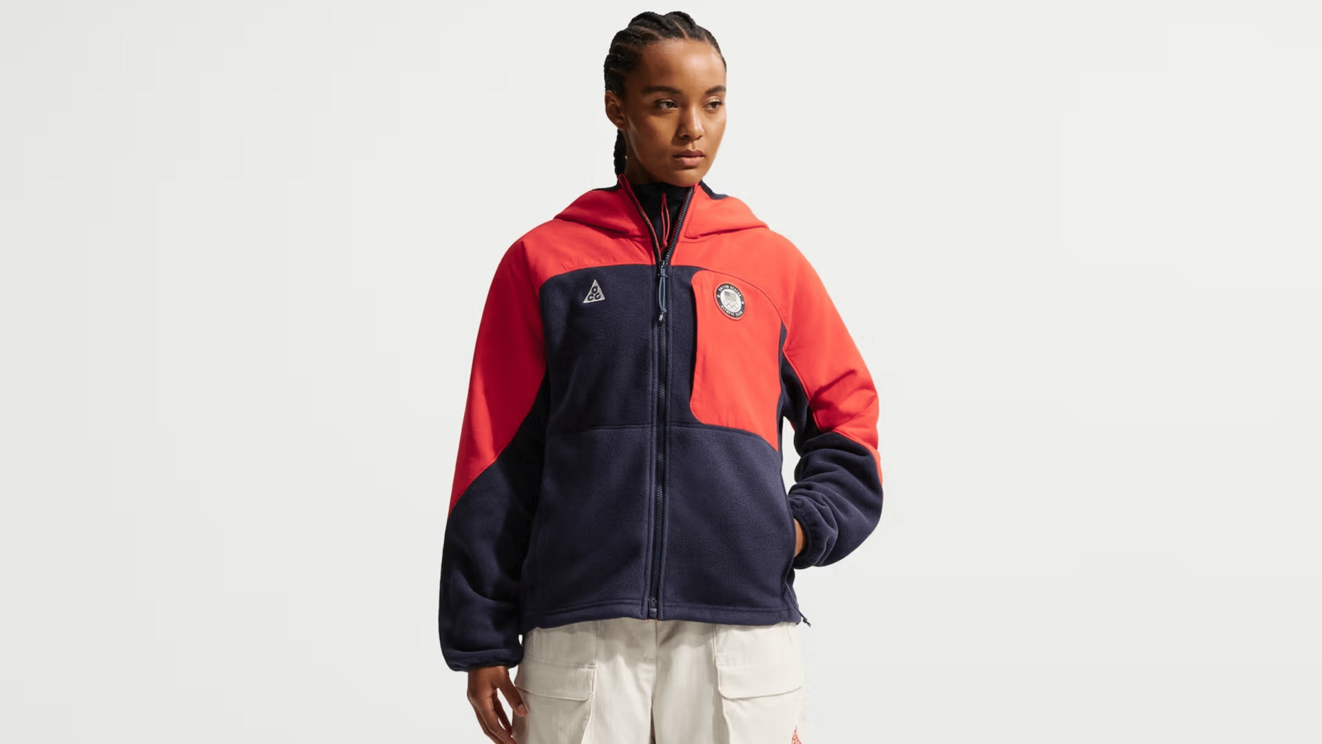 Woman models blue Nike Olympic long-sleeved shirt against a white backdrop.