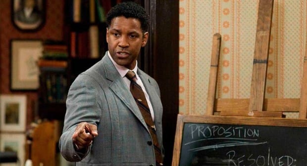 Screenshot of Denzel Washington in The Great Debaters, wearing glasses and a suit, addressing students with passion.