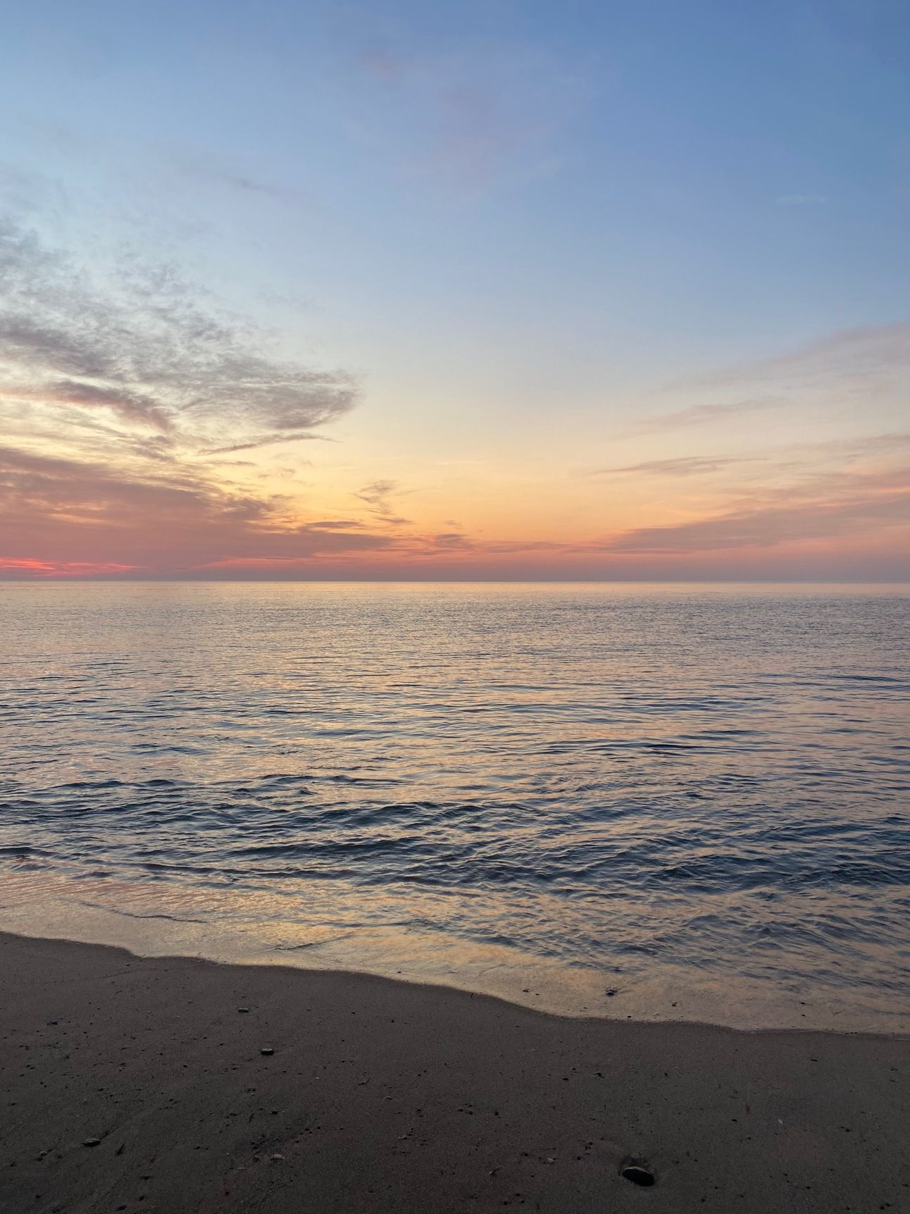 The ocean jst after sunset: silvery blue under a blue sky and pink horizon. 