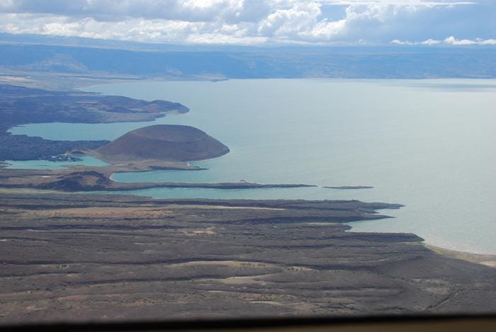 A small part of Lake Turkana with a rocky shoreline and a very conspicuous cone shaped mound.
