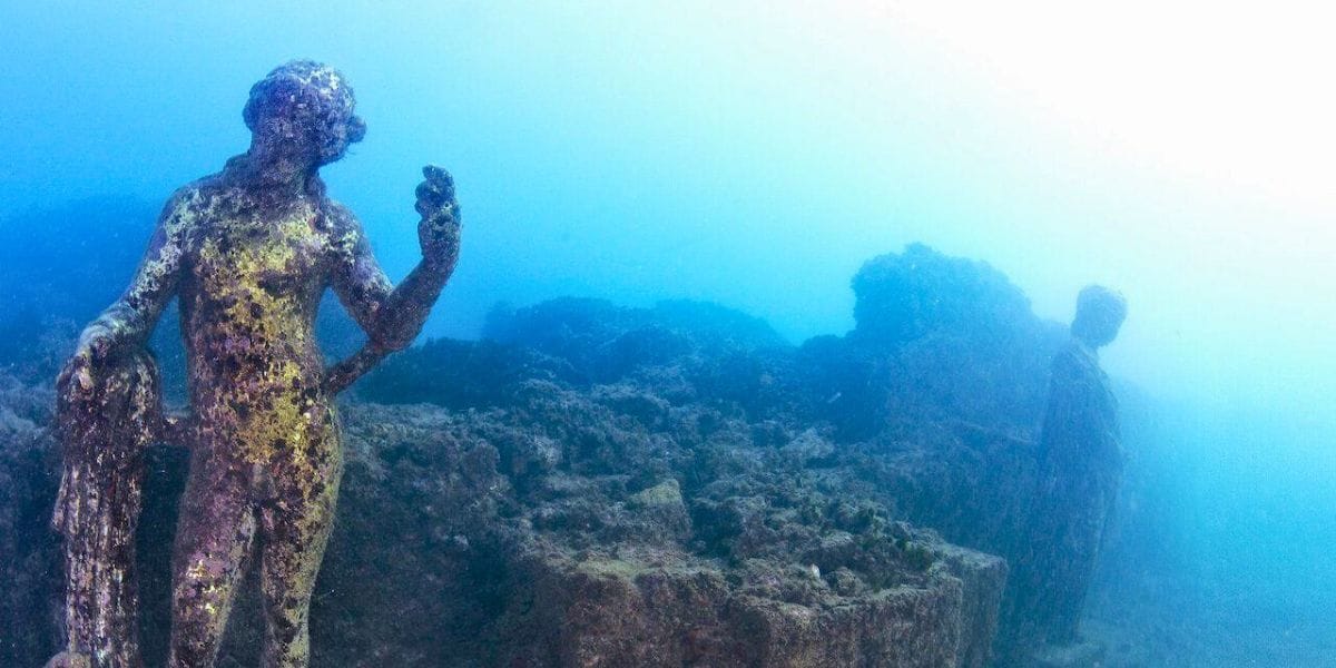 a statue underwater seen by scuba divers