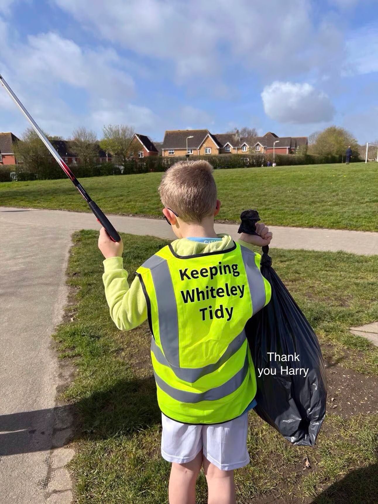 A child wearing a high vis and holding a bag and litter picker
