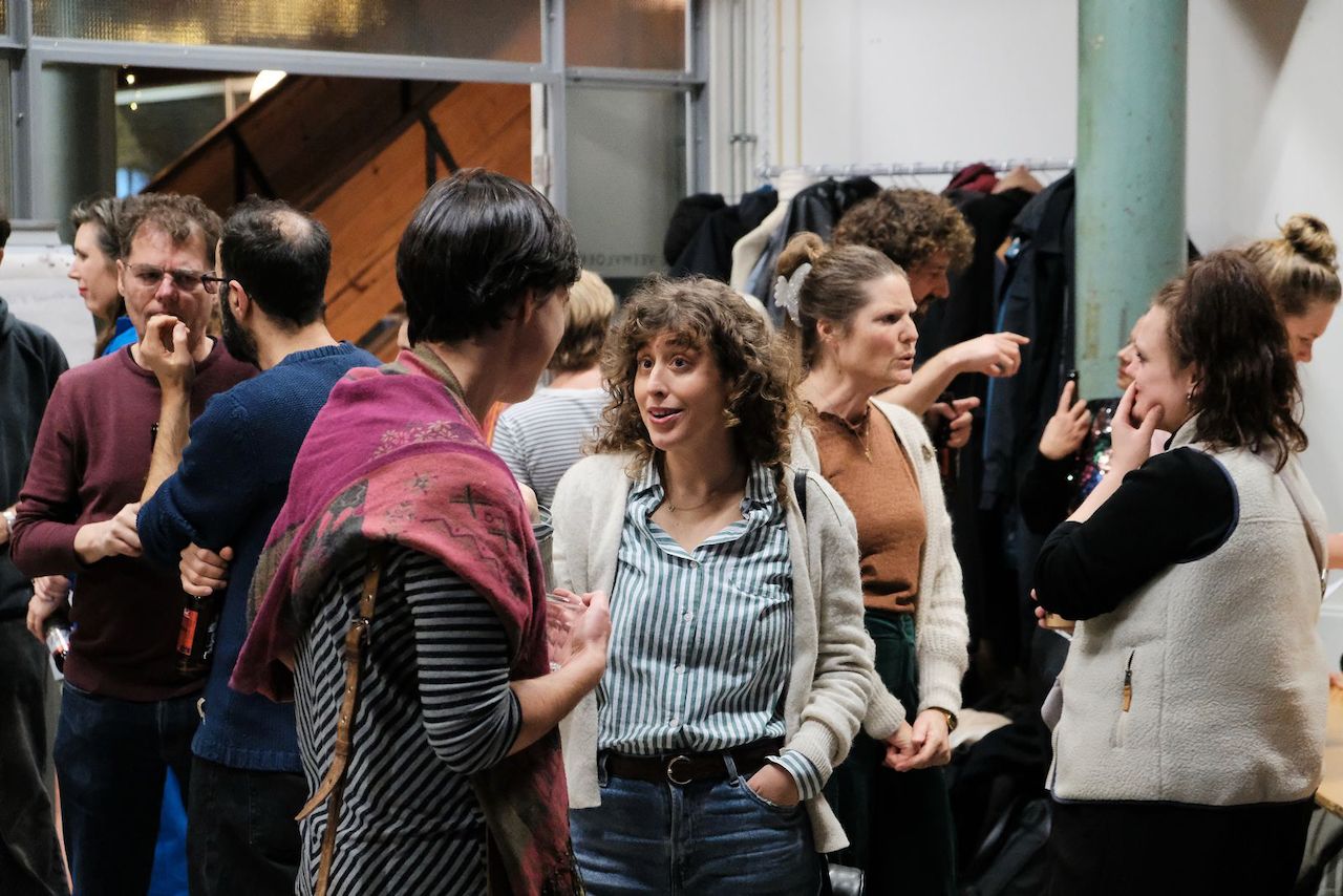 Foto van de vorige nieuwjaarsborrel. Een groep mensen staat in een zaal en is in verschillende groepjes met elkaar in gesprek.