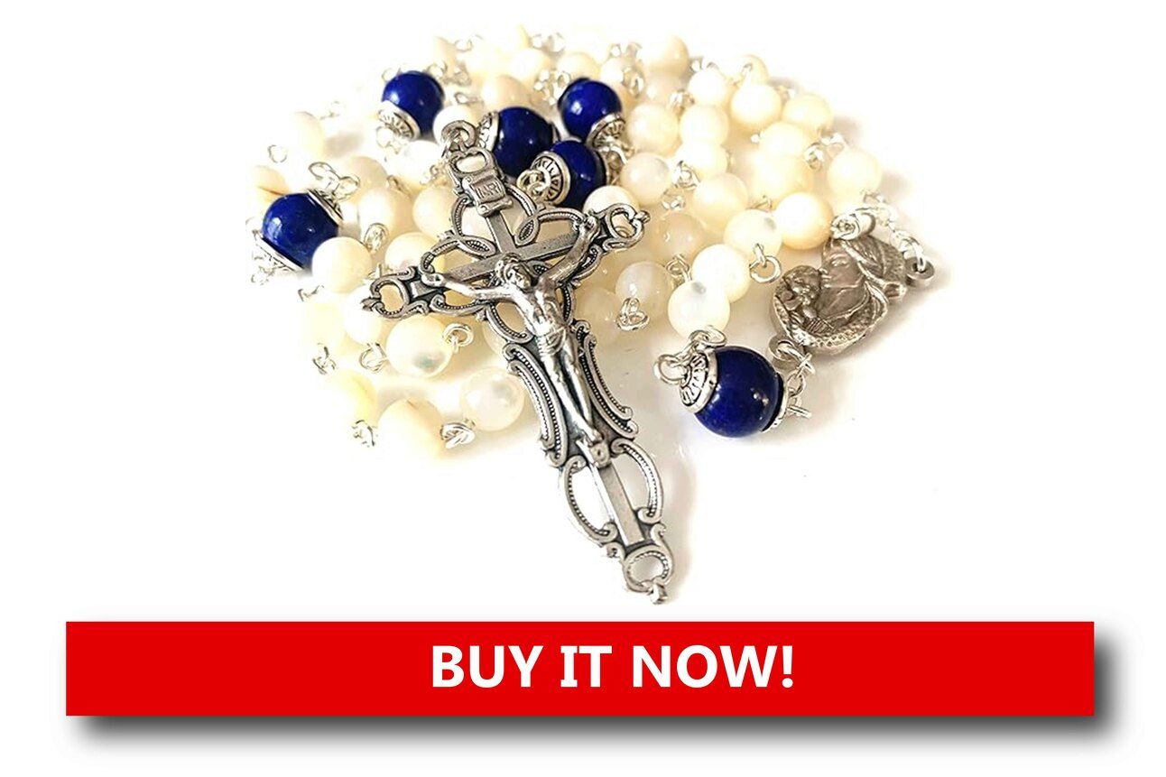 Mother of Pearl Prayer Beads Alt text: Shimmering mother of pearl prayer beads with a silver cross pendant and a white ribbon, resting beside a Christmas candle and greenery.