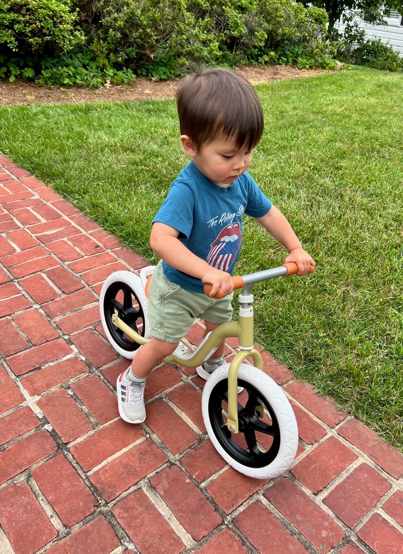 Young boy riding a balance bike on a paved path