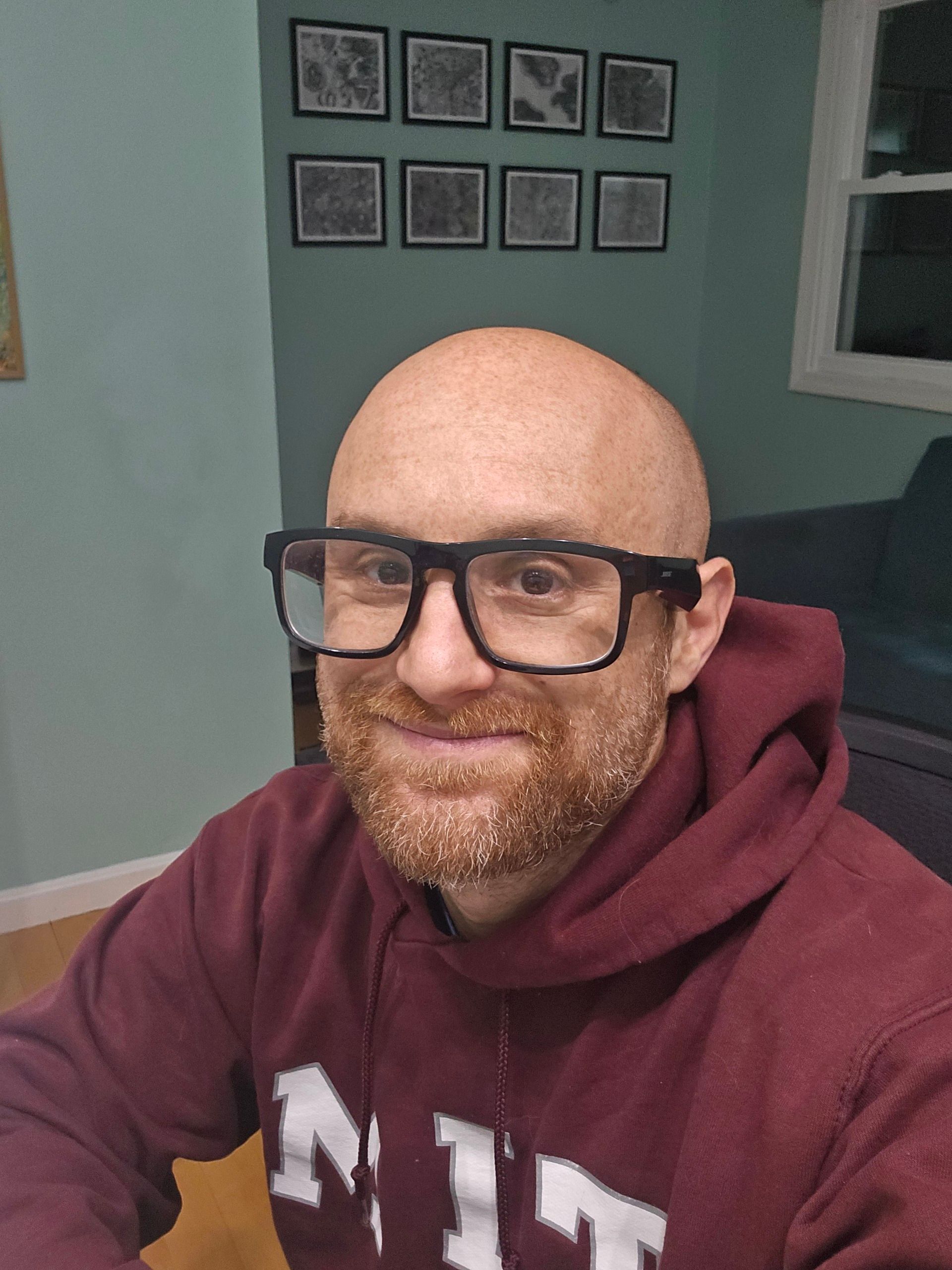 A selfie of me in a dimly lit home office with sea foam green walls. I’m a bald, middle-aged, white man with a red beard flecked with white. I’m wearing glasses with thick black rims and a maroon and white MIT sweatshirt.