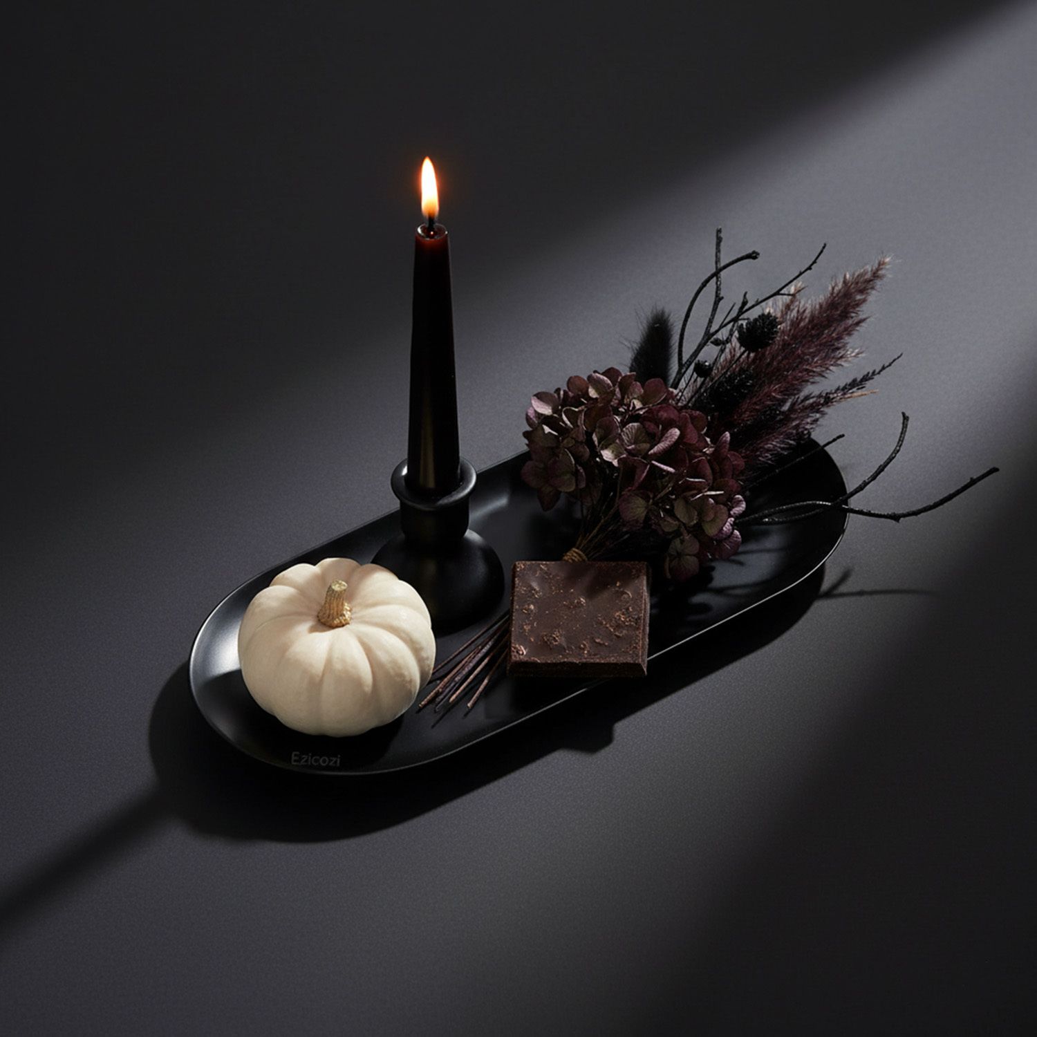An elegant flat lay of a black Ezicozi tray styled as a chic Halloween station with a candle and white pumpkin, promising a sophisticated and beautiful result.