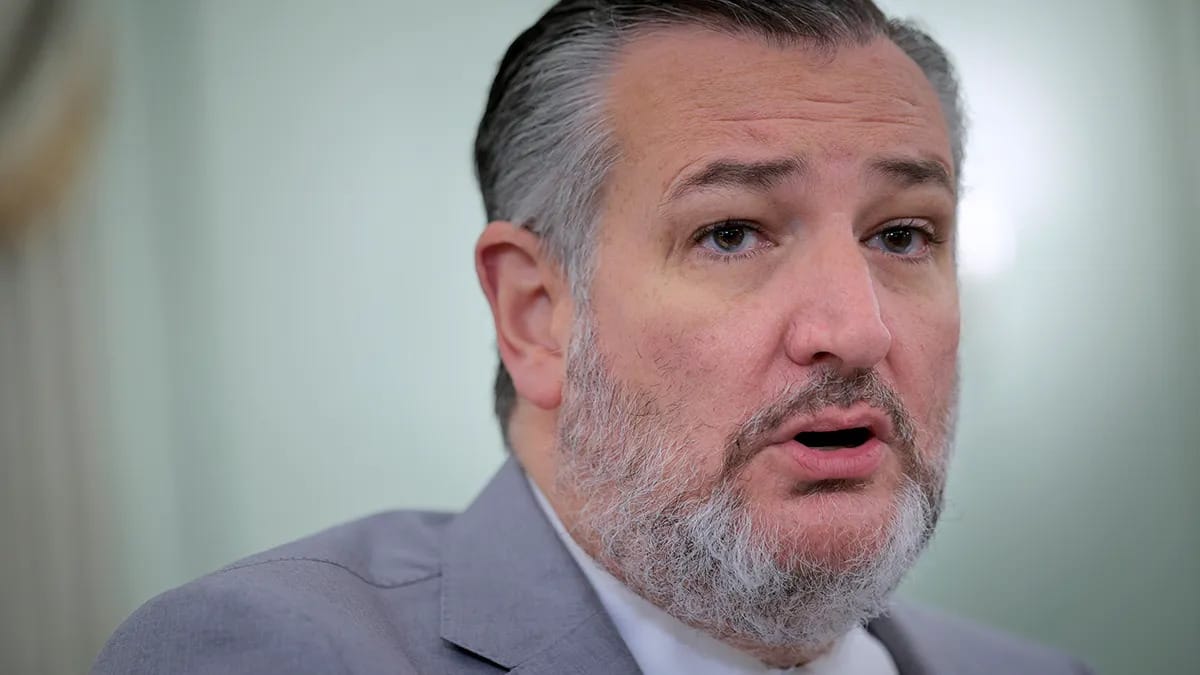 A Latino man wearing a gray suit is pictured speaking.