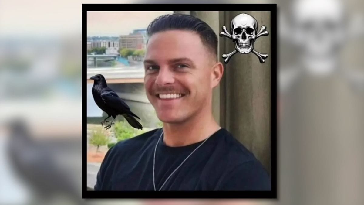 A man is shown smiling at the camera. A crow can be seen to his left, while a skull and crossbones is shown in the top right corner.