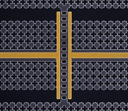 Scanning electron microscope image of a nanomechanical oscillator. Gold bars come in from the center right and left and the turn up and down to form Ts. They are separated by grey ovals and surrounded by grey squares.