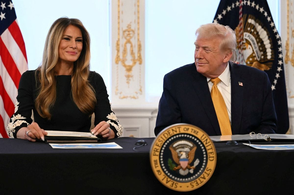 A white man smiles while looking at a white woman to his left who is also smiling.
