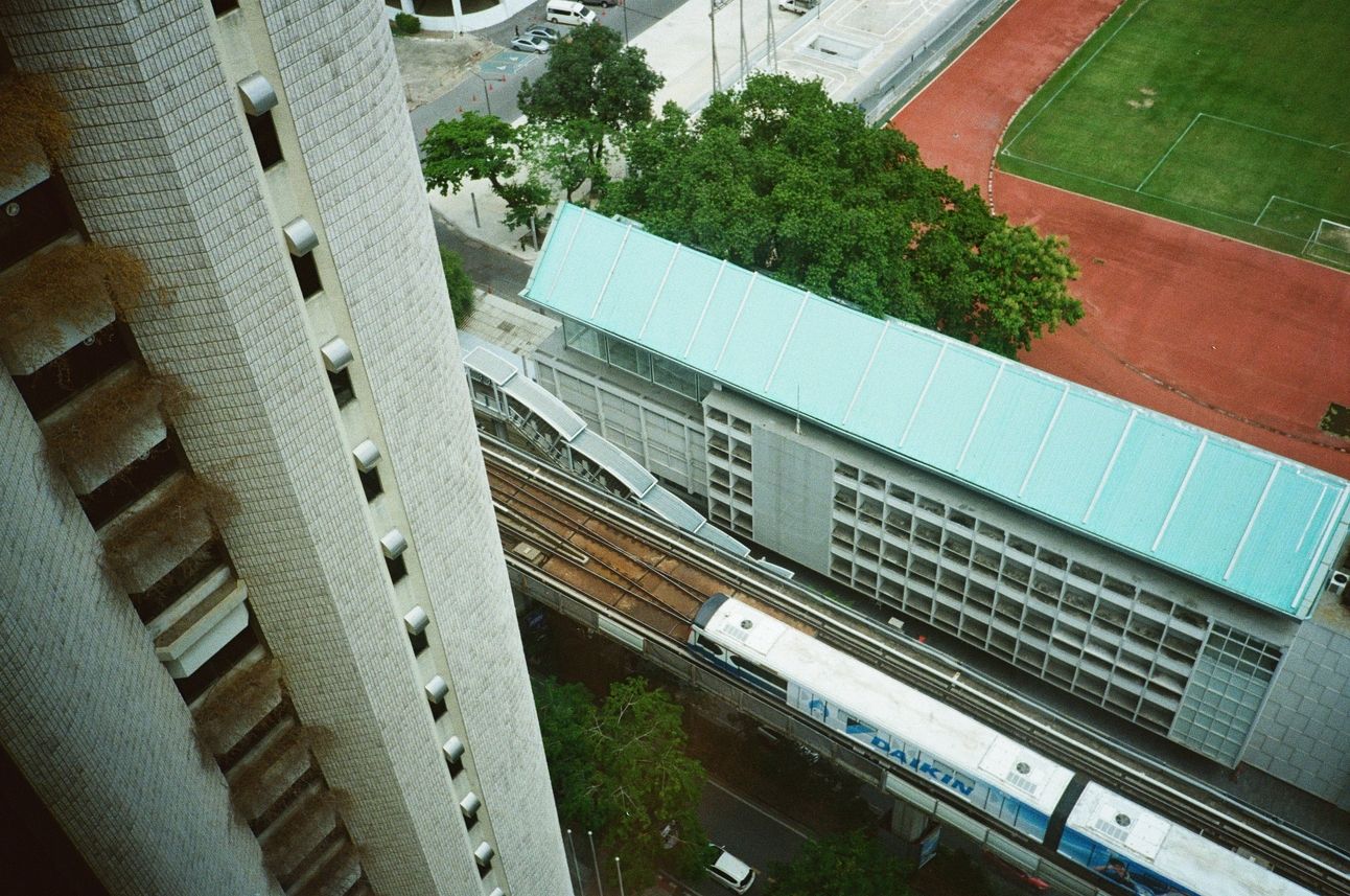 A skytrain passes by a soccer field.