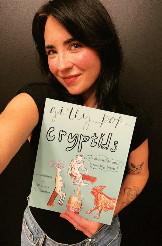 A photo of Mallory Huffstetler holding her book, "Girly Pop Cryptids"