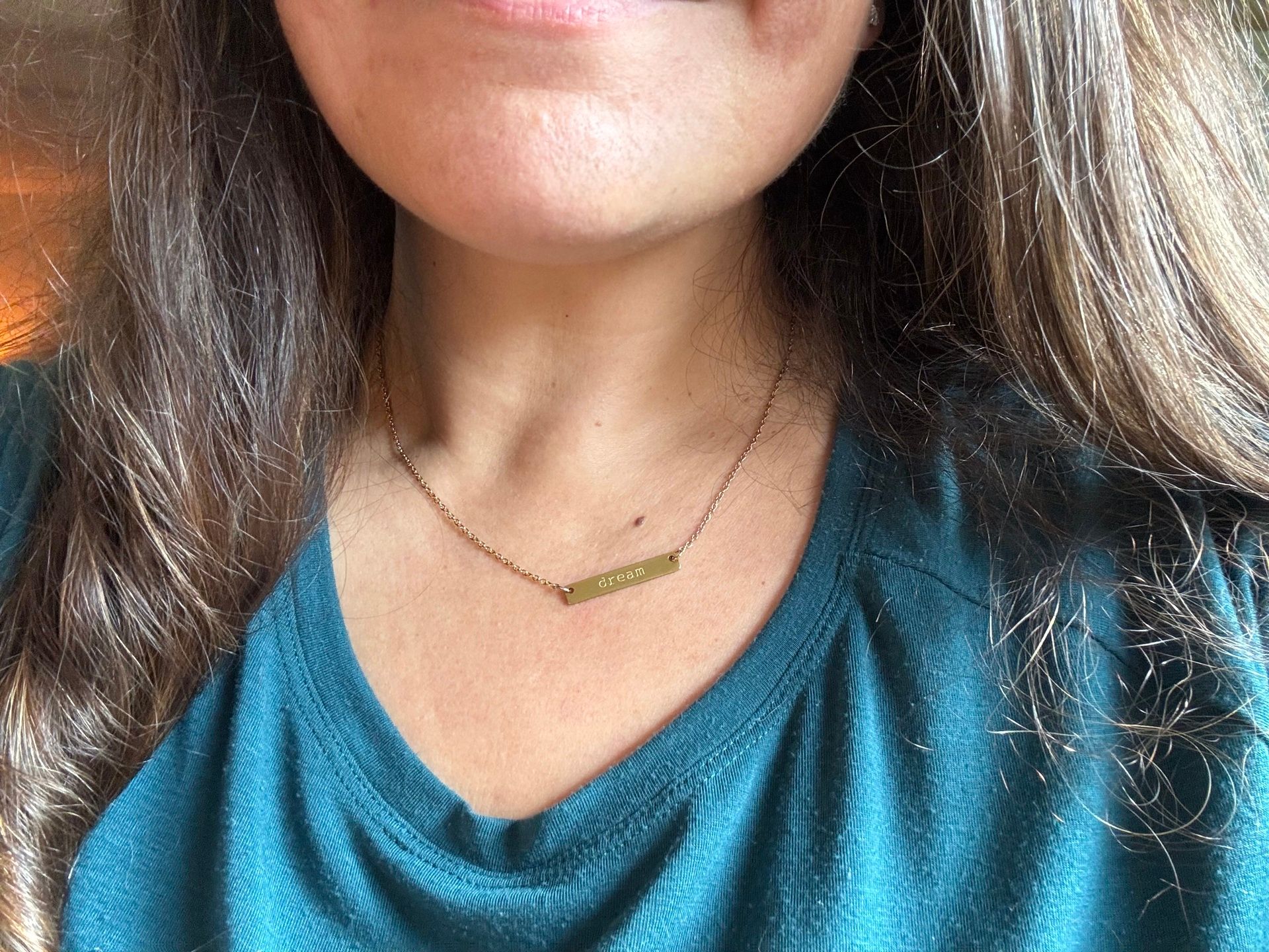 women wearing a gold necklace that says dream