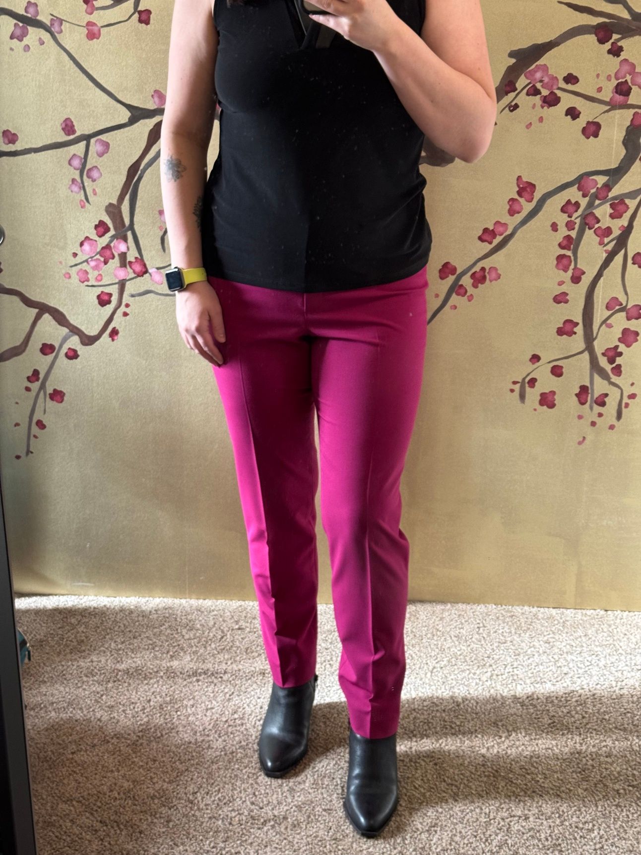 photo of a femine body in a black sleeveless blouse and pink pants.