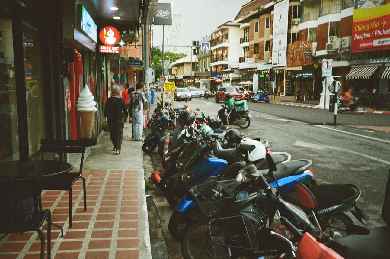 A street lined with shops and motor scooters parked along the street.