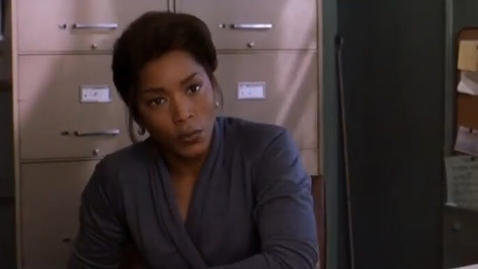 Screenshot of Angela Bassett in Music of the Heart, standing in a school hallway with a confident, supportive demeanor.