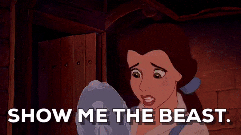 Disney character Belle from Beauty & the Beast holding up a mirror and looking in it intently as it glows with an electric yellow color. The text below Belle and her mirror reads, "SHOW ME THE BEAST." 