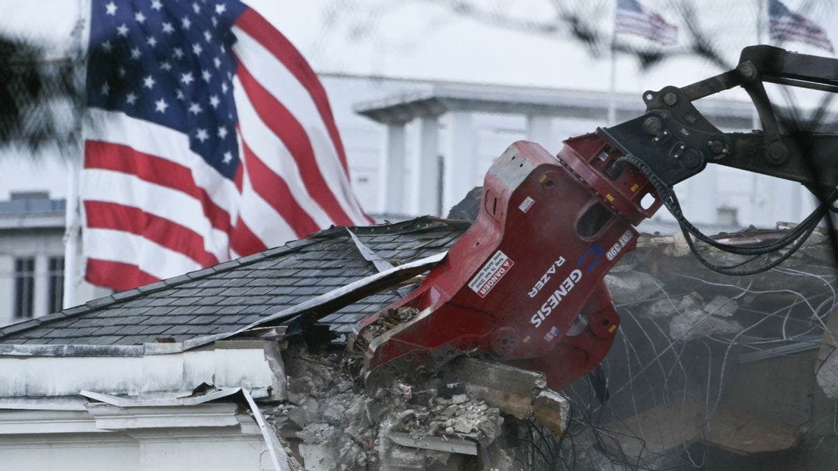 Demolition equipment is shown on what appears to be a roof. A red, white and blue flag can be seen in the background.