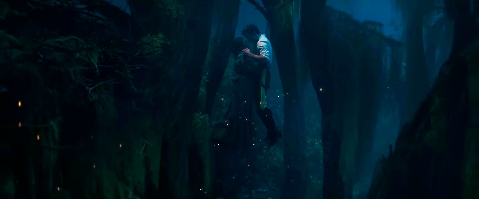 Cynthia Erivo as Elphaba (left) and Jonathan Bailey as Fiyero (right) in WICKED: FOR GOOD. The lighting is horrendous, but she's wearing a gray duster cardigan and he is wearing a white shirt and his military uniform pants. They're mid-air and there are yellow lights around them.