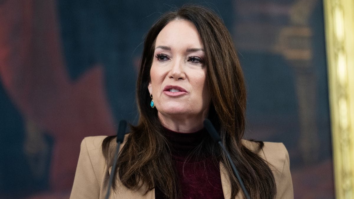 A white woman looks to the left while speaking.
