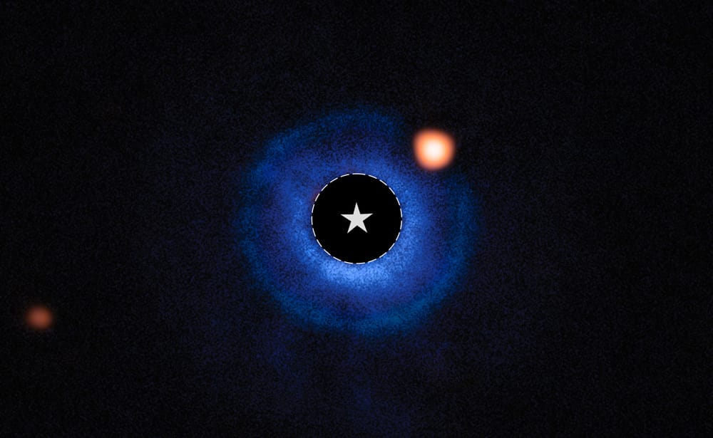 A broad blue ring of material with a black center where the star is masked out. A bright orange blob is at the 2 o’clock position in the outer part of the ring.