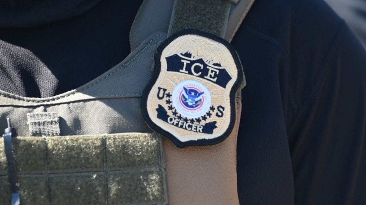 A yellow badge that says ICE US OFFICER is shown on someone's arm.