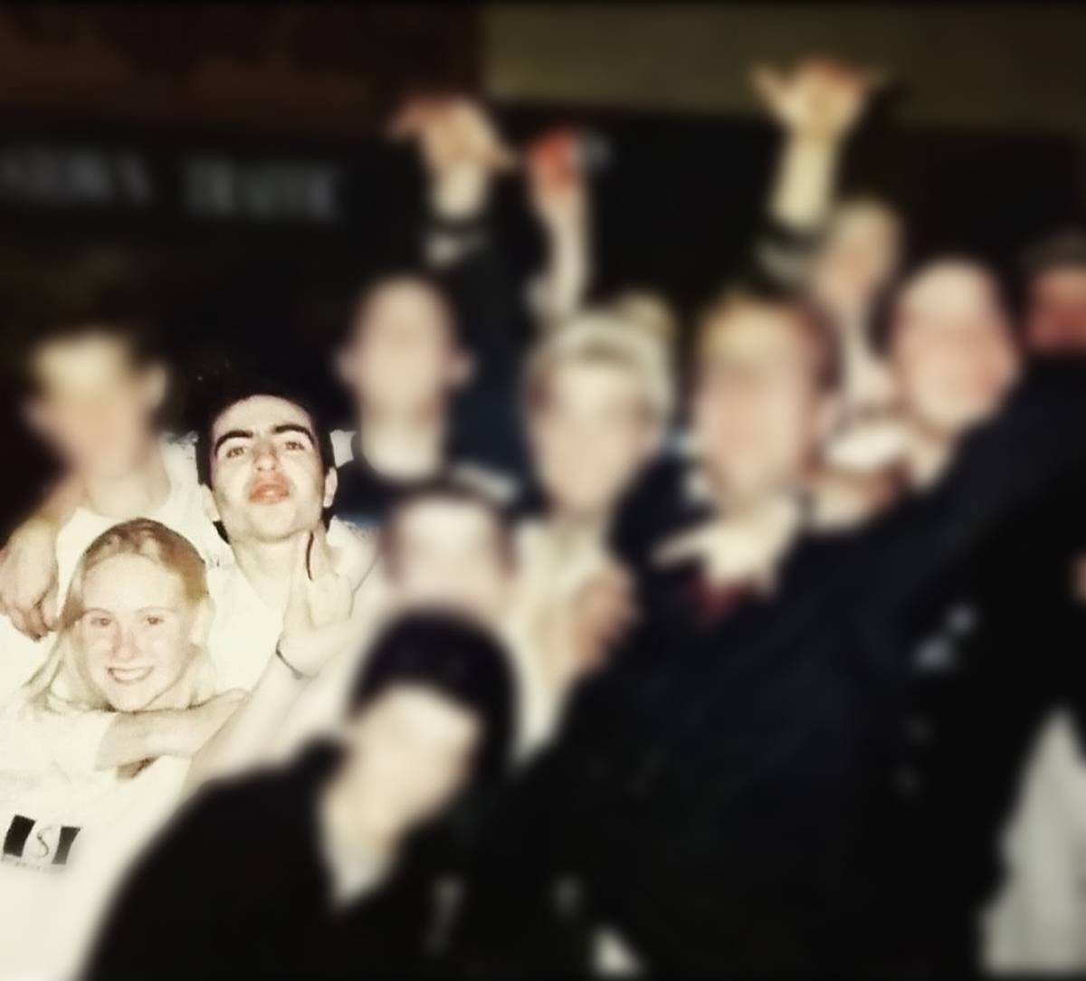 A photo of people, mostly blurred out. Visible are a young teenage girl with blond hair and a man with dark hair next to her.