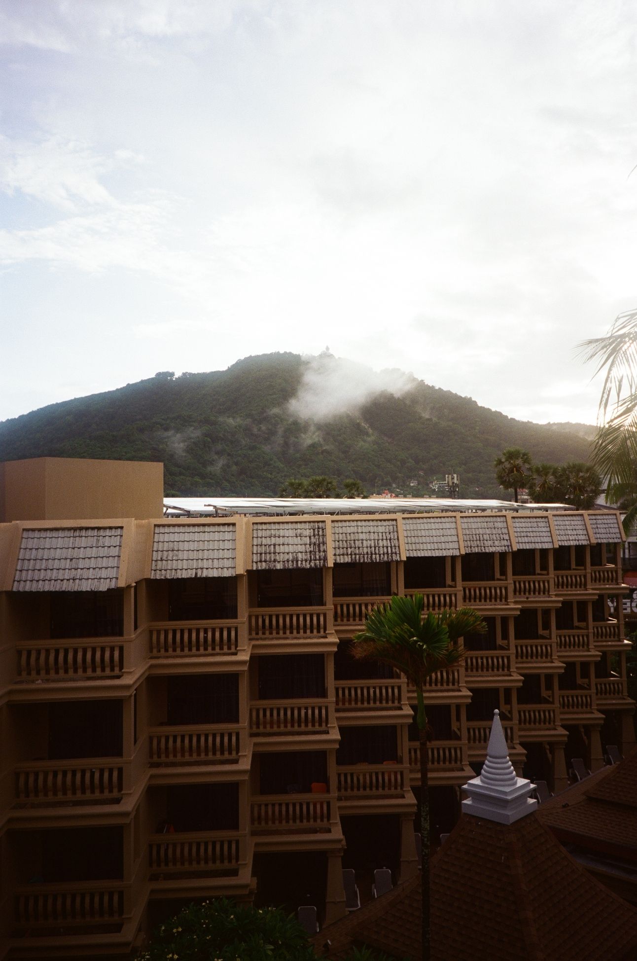 A mountain rises beyond a resort with a giant buddha statue at the summit.