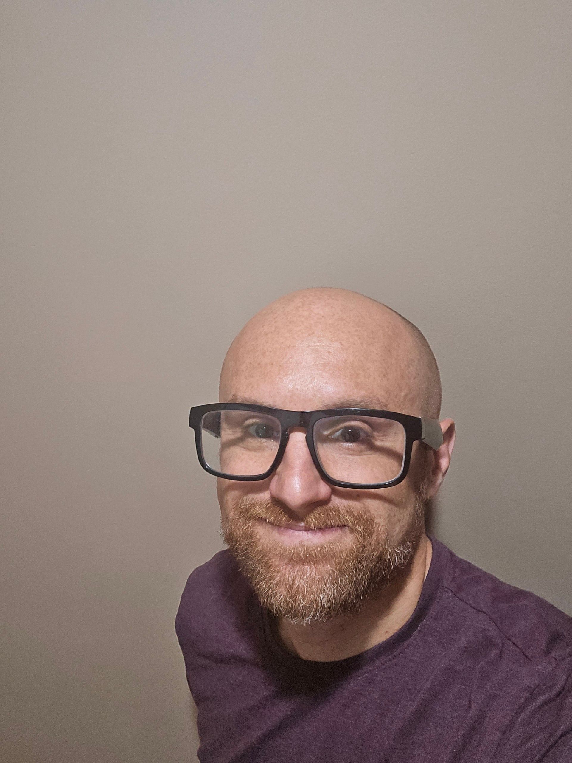 A selfie of me in front of a brown background. I'm a bald, middle-aged, white man with a red beard flecked with white. I'm wearing glasses with thick black rims and a maroon t-shirt.