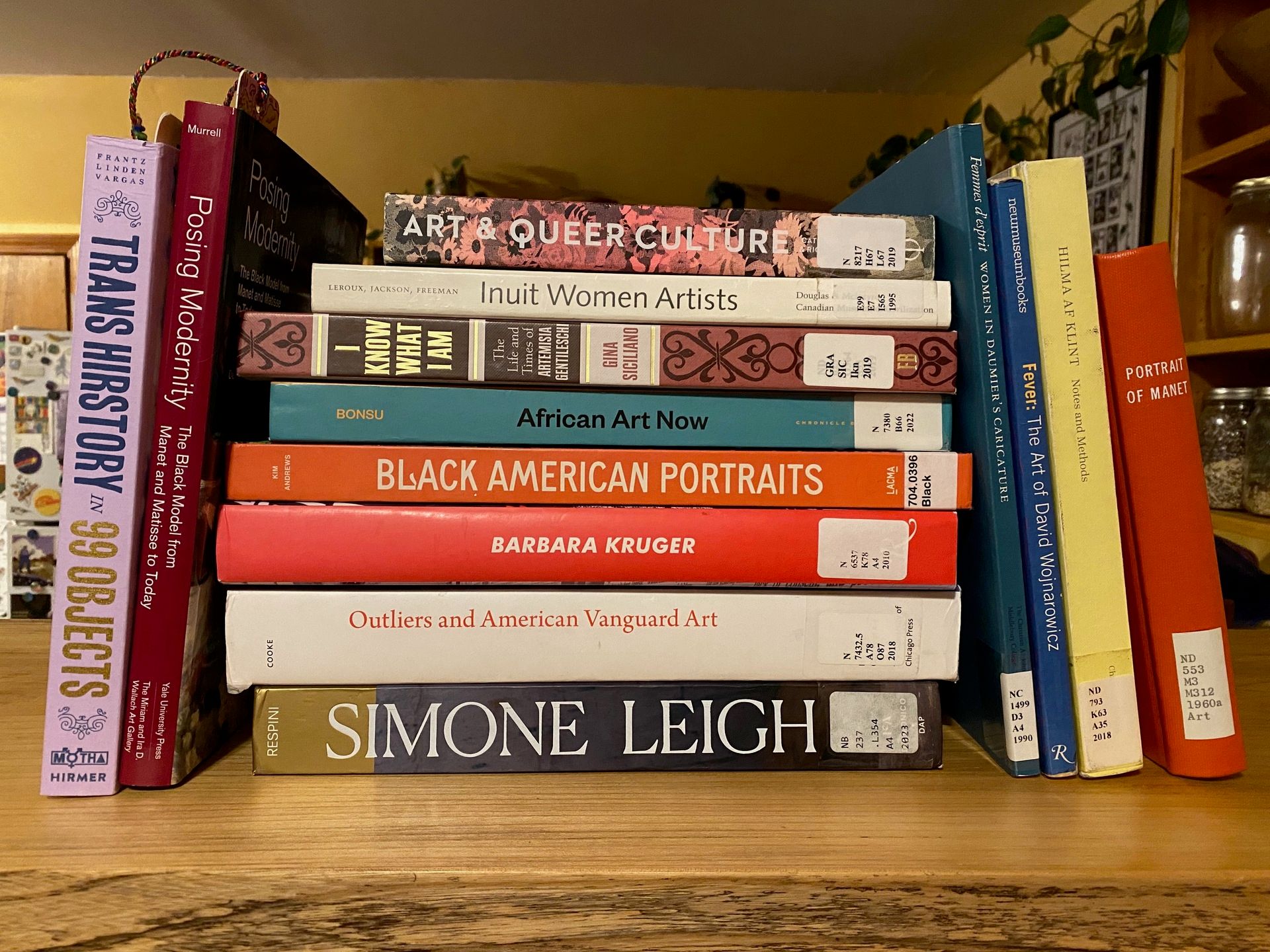 A large stack of art books, some standing up right and some piled on top of each other, on my kitchen counter.